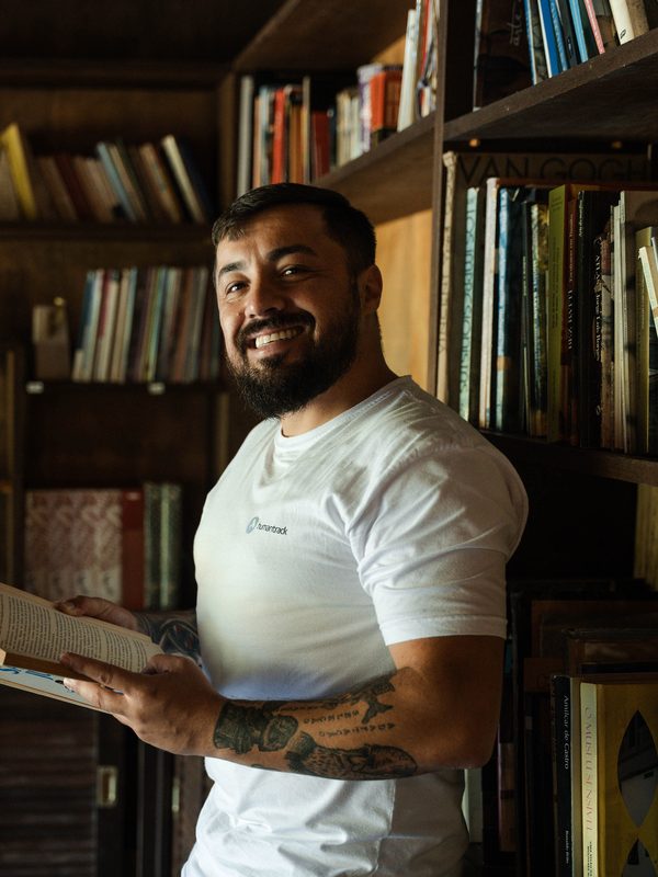 Júlio Gonçalves diante de uma estante de livros, com um livro aberto nas mãos